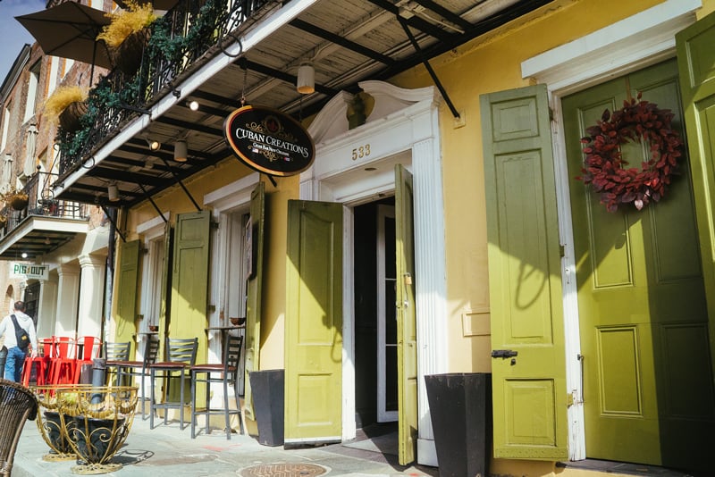 Exterior of Cuban Creations cigar bar at 533 Toulouse Street in the New Orleans French Quarter, with green shutters and sidewalk seating